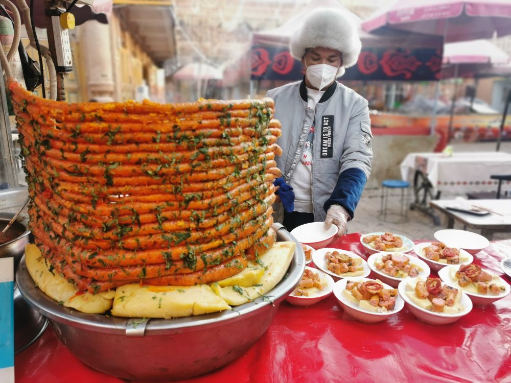 12月14日,在喀什古城美食街上,商户正给客人准备小吃。(新华社记者刘红霞 摄)