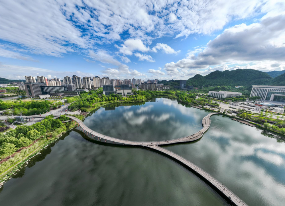 2024年5月4日,人们在贵州省遵义市新蒲新区天鹅湖湿地公园的廊桥上