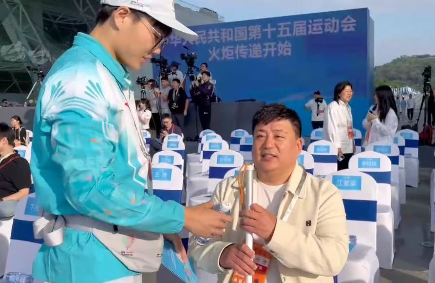 11月2日,李广洲拄着盲杖,在引导员带领下在第十五届全国运动会深圳火炬传递活动现场落座。新华社发