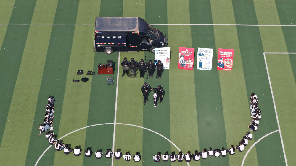 　　↑ 4月15日，在江苏省淮安市洪泽湖实验小学，民警给小学生讲解警用装备知识（无人机照片）。新华社发（殷潮摄）